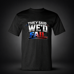 They Said We’d Fail black trucker T-shirt on charcoal studio background